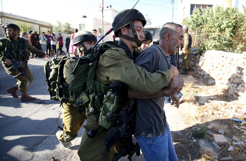 © Reuters. Israeli soldier detains a Palestinian during confrontations in Qafr Malik village near the West Bank city of Ramallah 