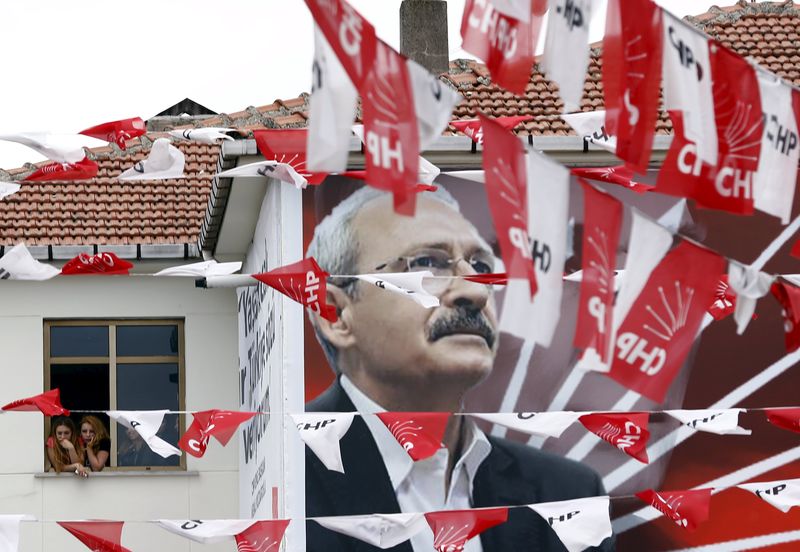 © Reuters. Women standing at a window listen to pro-Kurdish Peoples' Democratic Party co-chair Demirtas, as a poster of main opposition Republican People's Party leader Kilicdaroglu is seen in the foreground, during an election rally in Istanbul, Turkey