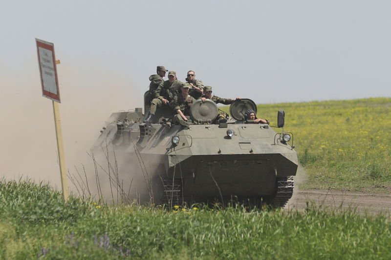 © Reuters. Men wearing military uniforms ride atop APC during training session at Kuzminsky military training ground in Rostov region