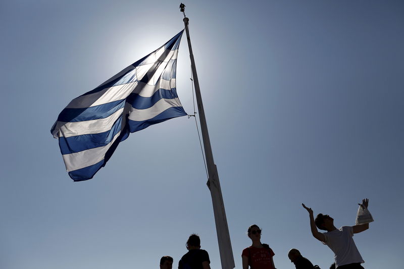 © Reuters. Turistas sob a bandeira da Grécia em Atenas