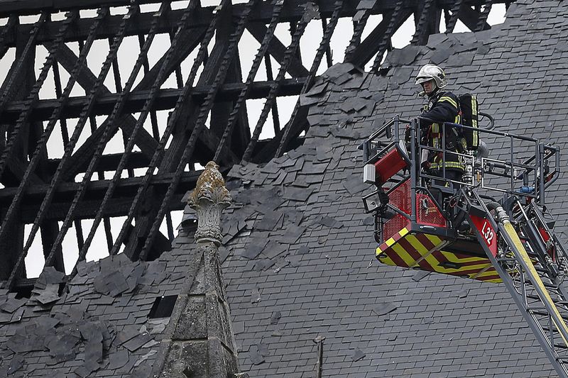 © Reuters. French firefighters on a rescue ladder stands in front of the fire-damaged roof of the Saint Donatien Basilica in Nantes