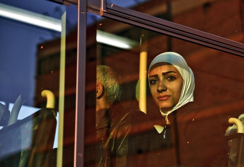© Reuters. Syrian refugee woman sits in a bus after after arriving in the port of Piraeus near Athens