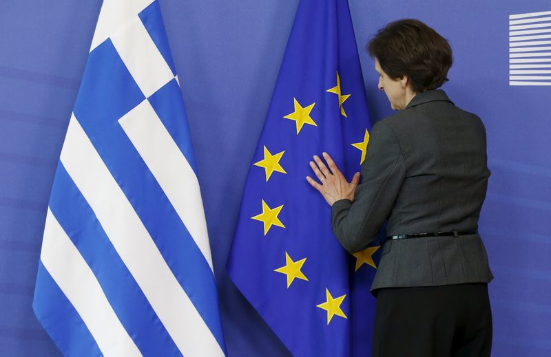 © Reuters. Mulher arrumando bandeiras da Grécia e União Europeia durante evento em Bruxelas