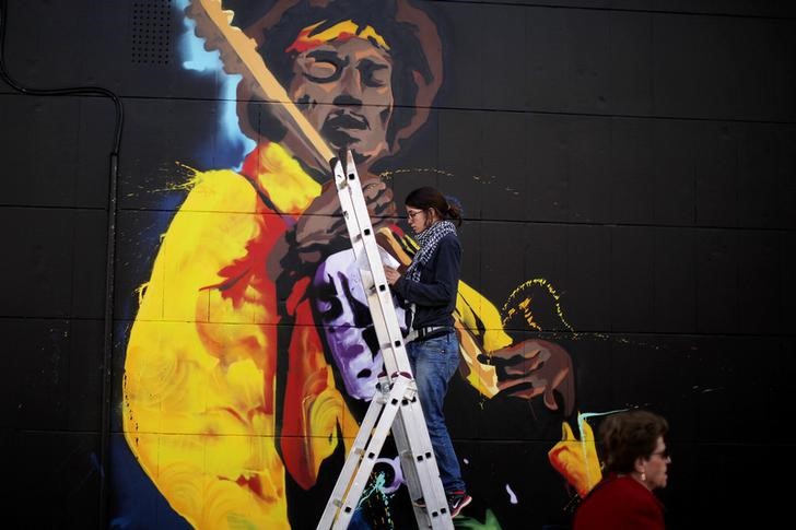 © Reuters. Mulher pinta grafite de Jimi Hendrix em Málaga, na Espanha