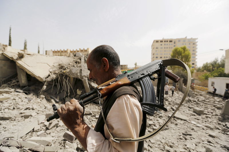 © Reuters. Guarda passa por casas de houthis destruídas em ataque aéreo de coalizão saudita em Sanna, no Iêmen