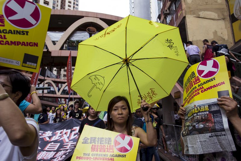 © Reuters. Pro-democracy protester holds a yellow umbrella, the symbol of the Occupy Central movement, during a march to demand lawmakers reject a Beijing-vetted electoral reform package for the city's first direct chief executive election in Hong Kong, China 