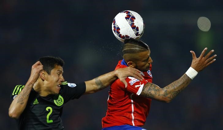 © Reuters. Arthuro Vidal, do Chile, cabeceia a bola marcado pelo mexicano Julio Domínguez em partida da Copa América