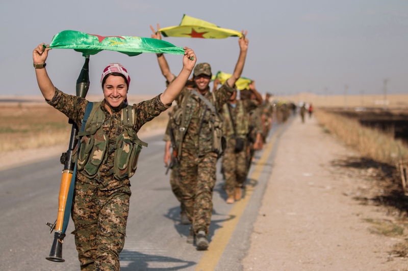 © Reuters. Kurdish fighters gesture while carrying their parties' flags in Tel Abyad of Raqqa governorate after they said they took control of the area 