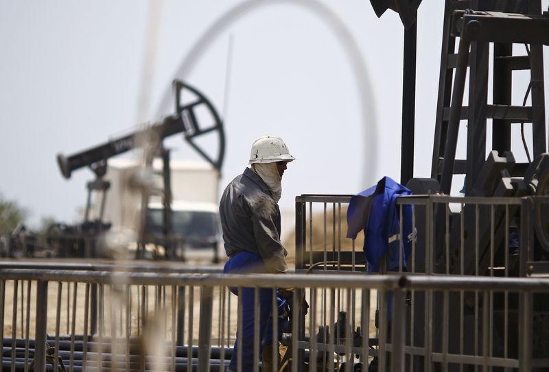 © Reuters. A worker rests next to an oil pump on a sunny day in Baku