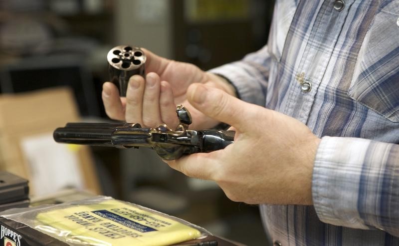 © Reuters. Chris Dogolo inspects a Colt Single Action Army revolver in Guilford