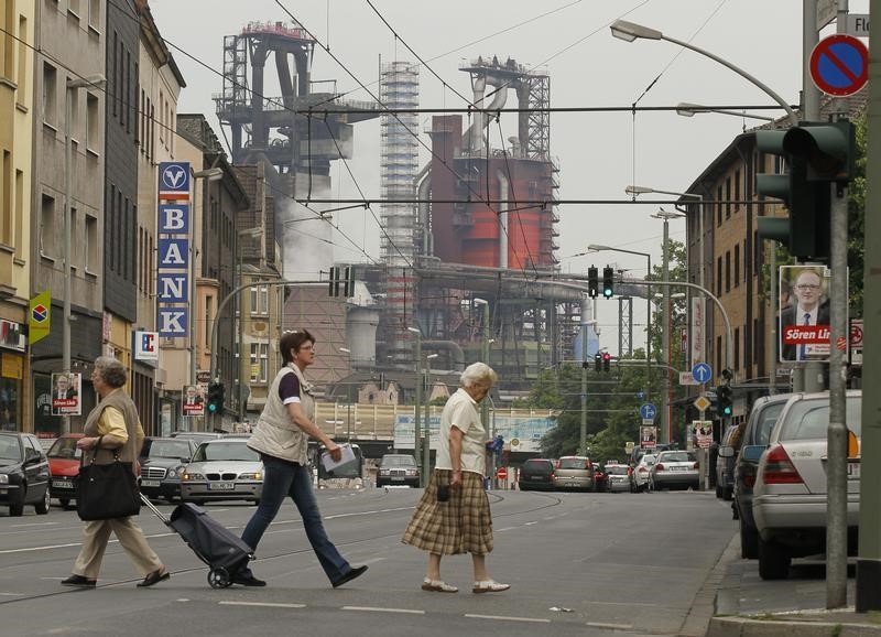 © Reuters. People cross a street in front of a steelworks of German steelmaker ThyssenKrupp AG in Duisburg