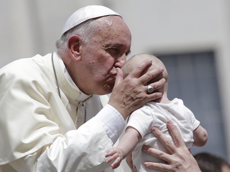 © Reuters. Pope Francis kisses a baby as he leaves at the end of his Wednesday general audience in Saint Peter's square at the Vatican