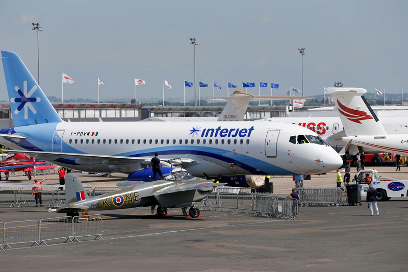 © Reuters. Workers move a Sukhoi Superjet 100 airplane into a static display two days before the opening of the 51st Paris Air Show at Le Bourget airport near Paris