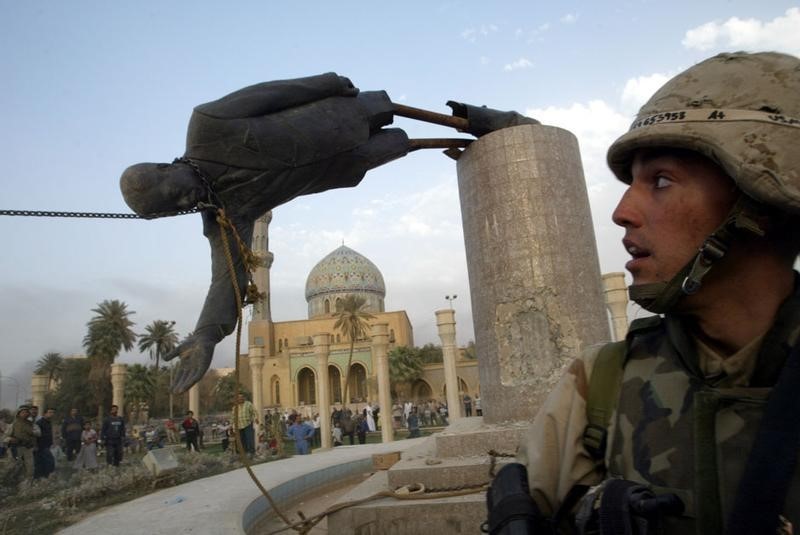© Reuters. A U.S. MARINE WATCHES A STATUE OF PRESIDENT SADDAM HUSSEIN FALL IN
CENTRAL BAGHDAD.