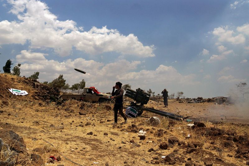 © Reuters. Free Syrian Army fighters fire rockets towards forces loyal to Assad in the northern countryside of Quneitra, Syria