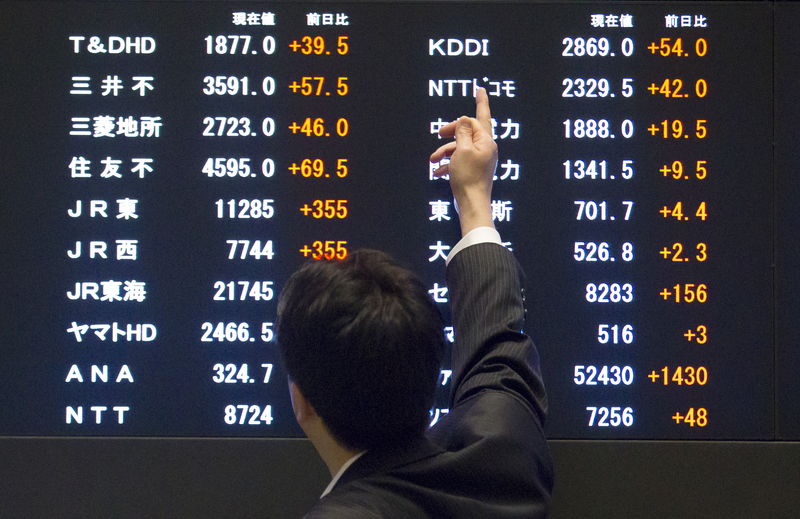 © Reuters. A man points at market indices at the Tokyo Stock Exchange
