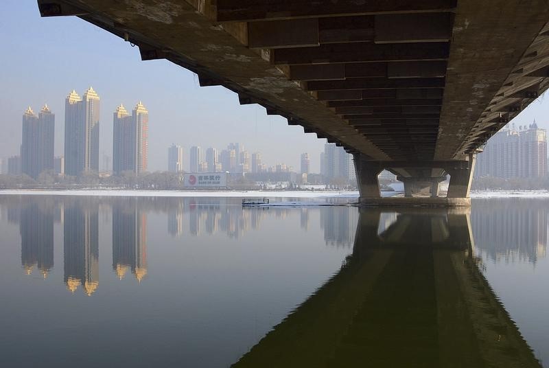 © Reuters. Newly-built residential buildings are seen next to the partially-frozen Songhua River and a bridge in Jilin