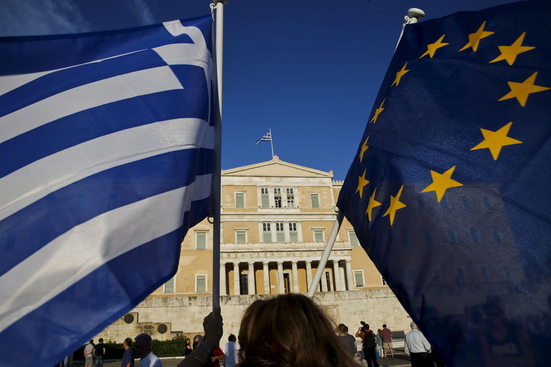 © Reuters. Mulheres com bandeiras da UE e da Grécia do lado de fora do Parlamento grego, em Atenas
