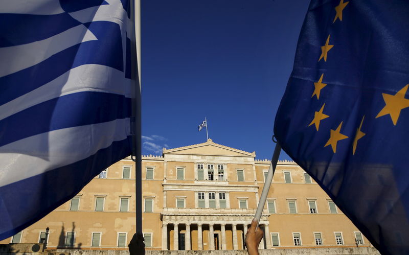 © Reuters. Protesters hold an EU flag and a Greek flag in front of the parliament in Athens