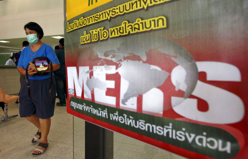 © Reuters. A woman wearing a mask walks past an information banner on MERS at the entrance of Bamrasnaradura Infectious Diseases Institute in Nonthaburi province