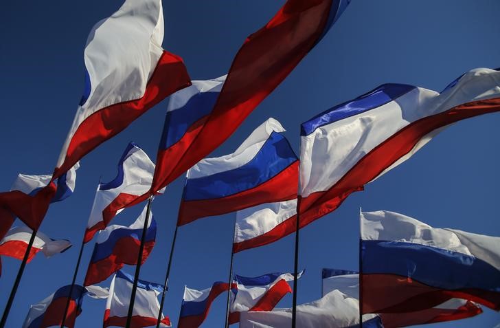 © Reuters. Russian and Crimean flags flutter in wind during celebrations marking first anniversary of Russia's annexation of Crimea in Simferopol