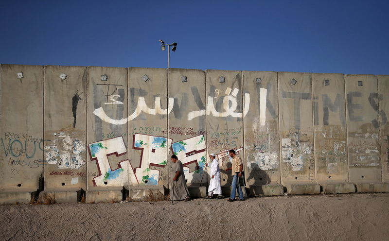 © Reuters. Palestinos passam pelo controverso muro israelense perto de Ramallah