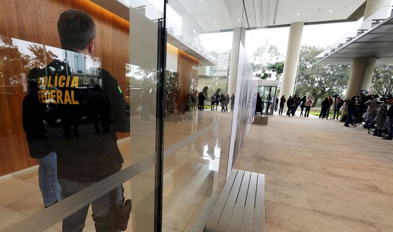 © Reuters. Agentes da Polícia Federal observam jornalistas no lado de fora da sede da Odebrecht, em São Paulo.