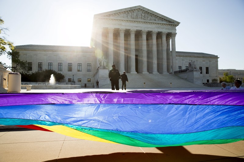 © Reuters. Gay marriage supporters hold a gay rights flag in front of the U.S. Supreme Court before a hearing about gay marriage