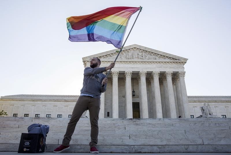 © Reuters. Vin Testa of Washington, DC, waves a gay rights flag in front of the U.S. Supreme Court before a hearing about gay marriage