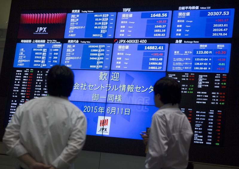 © Reuters. Men look at a display showing market indices at the Tokyo Stock Exchange 