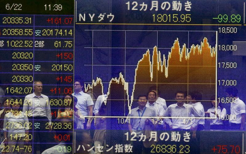 © Reuters. People are reflected in an electronic board displaying market indices in Tokyo