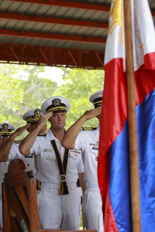 © Reuters. U.S. Navy Rear Admiral William Merz salutes to a Philippine  flag during the opening ceremony of Cooperation Afloat Readiness and Training (CARAT) 2015 at the Navy headquarters in Puerto Princesa city, Palawan