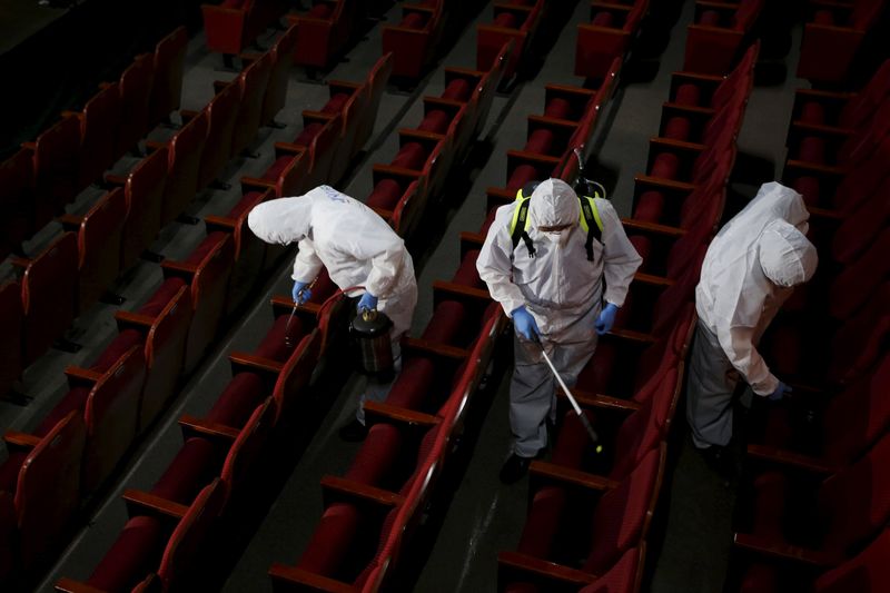 © Reuters. Employees from a disinfection service company sanitize the interior of a theater in Seoul