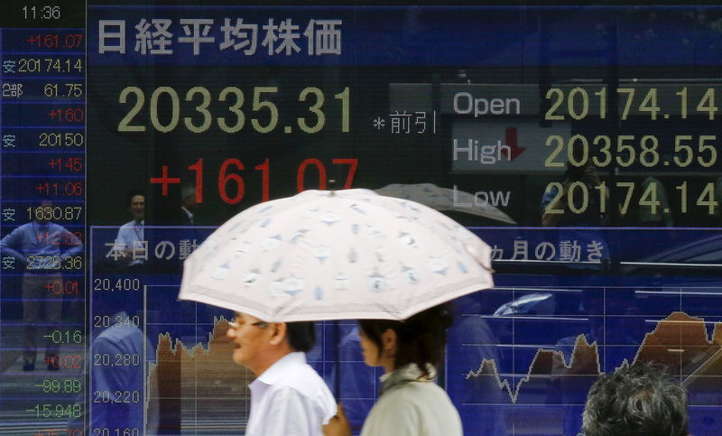 © Reuters. People walk past electronic board displaying market indices in Tokyo