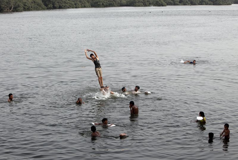 © Reuters. Men and children cool off during intense hot weather at China Creek in Karachi 