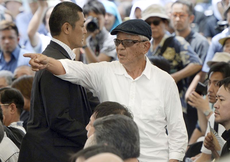 © Reuters. Man speaks out in protest against Japan's PM Abe during a memorial service to mark the 70th anniversary of the end of the Battle of Okinawa, at the Peace Memorial Park in Itoman, on Japan's southern island of Okinawa