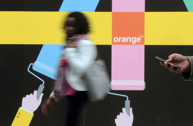 © Reuters. A man checks his mobile phone as he stands in front of a French telecom operator Orange store under construction in Paris