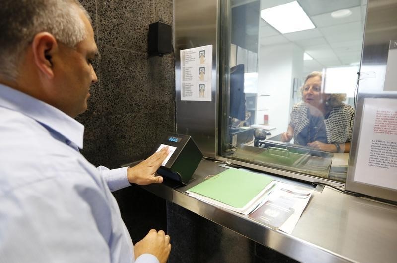 © Reuters. A man has his fingerprints electronically taken while taking part in a visa application demonstration at the U.S. Embassy in Lima