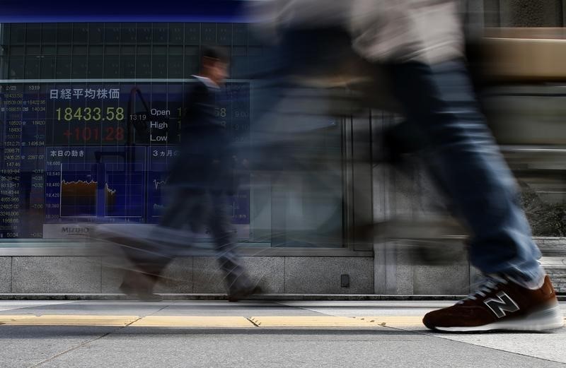 © Reuters. Pedestrians walk past an electronic board showing Japan's Nikkei average outside a brokerage in Tokyo