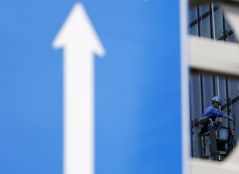 © Reuters. A worker cleaning glass windows is seen next to a traffic sign in Tokyo