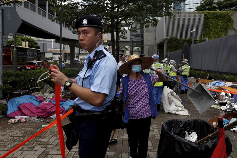 © Reuters. A policeman cordons off an area as a cleaner removes encampments outside the government headquarters in Hong Kong