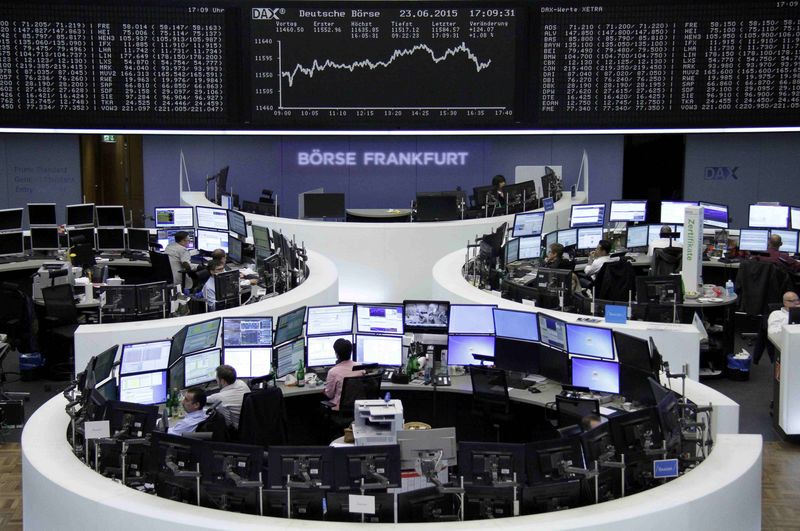 © Reuters. Traders work at their screens in front of the German share price index DAX board at the stock exchange in Frankfurt 