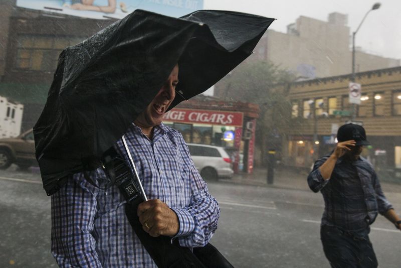 © Reuters. Pedestres se protegendo de forte chuva em Nova York