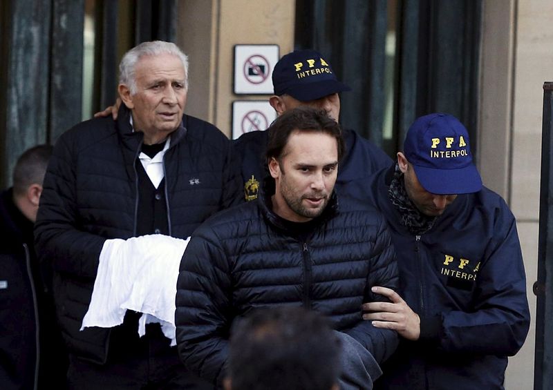 © Reuters. Argentine businessmen Jinkis and Hugo Jinkis who are wanted by U.S. prosecutors in a FIFA bribery investigation, are escorted by police officers after they turned themselves in on to authorities in Buenos Aires
