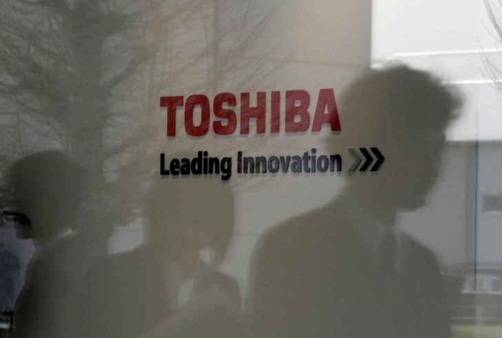 © Reuters. Logo of Toshiba Corp is seen as people are reflected on a window at the company's Hydrogen Energy R&D Center after its opening ceremony in Tokyo