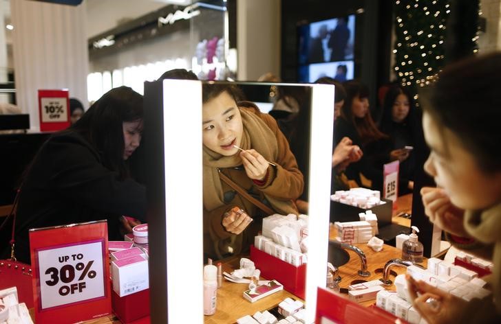 © Reuters. A shopper tries on some makeup as she hunts for bargains at Selfridges department store on the first day of their sales, in central London