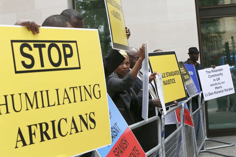 © Reuters. Protesters hold placards demanding the release of Rwanda's intelligence chief Karenzi Karake outside Westminster Magistrates Court in London