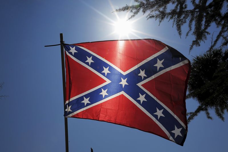 © Reuters. A Confederate flag is held up by a man at a rally outside the State House to get the Confederate flag removed from the grounds in Columbia