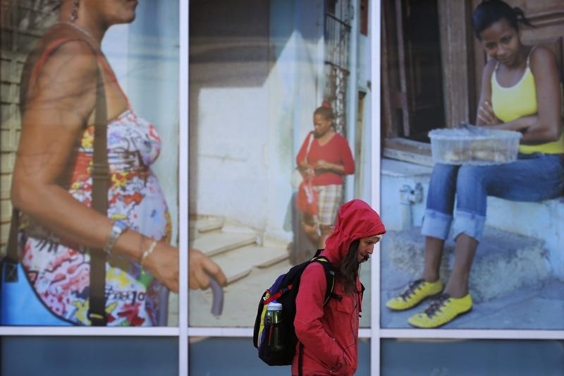 © Reuters. Pedestre passa por painel com fotos de Cuba em universidade nos EUA