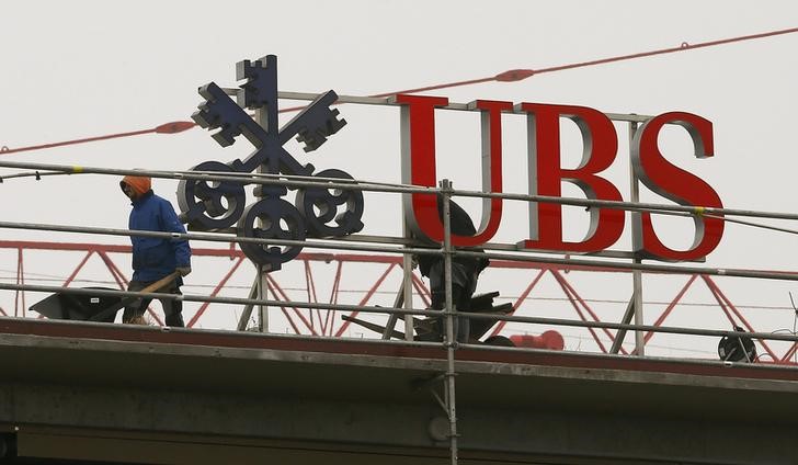 © Reuters. Workers are seen beside a logo of Swiss bank UBS in Zurich